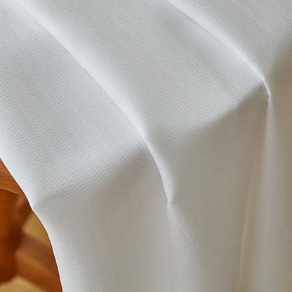 Gros plan sur la texture fluide et légèrement texturée du voilage blanc en polyester