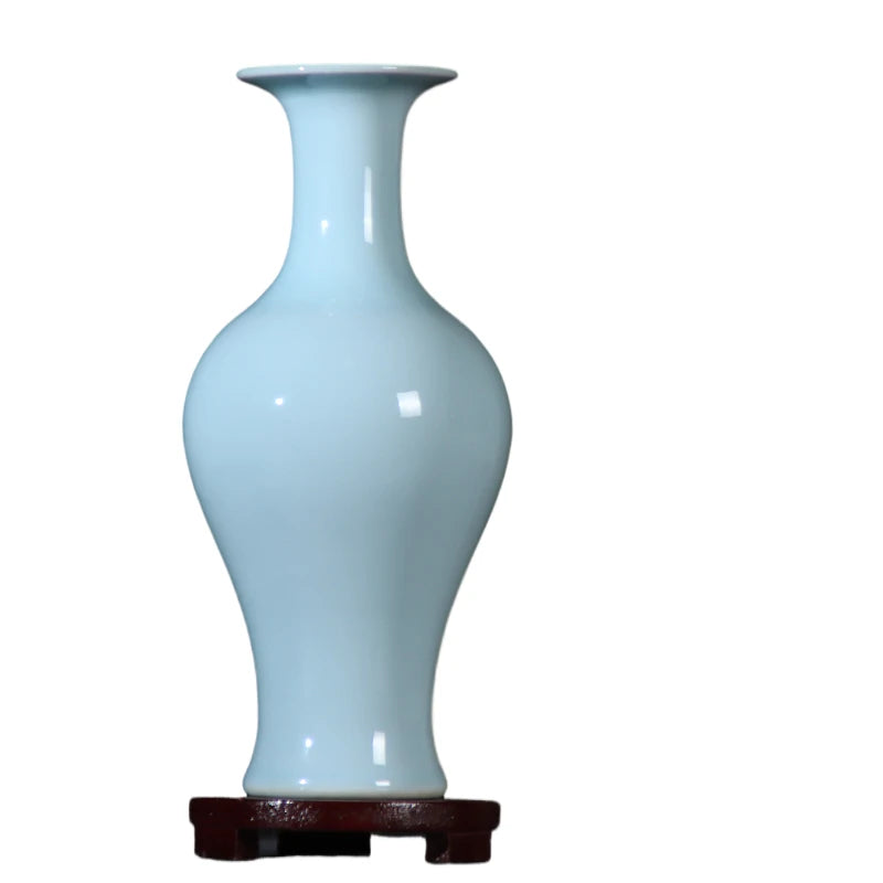 Vase décoratif en céramique bleu clair sur support en bois sombre.