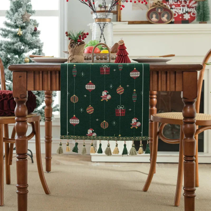 La table est agrémentée d'un chemin de table aux motifs de Noël, avec des boules, des cadeaux et des silhouettes de Père Noël, créant une ambiance festive et chaleureuse.
