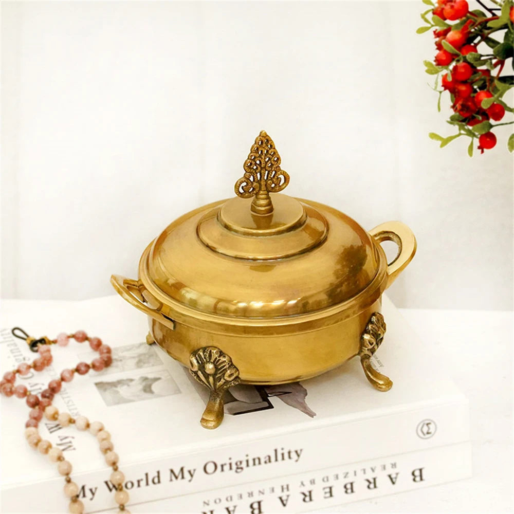 Un délicieux récipient doré orné de détails élégants, entouré de décorations rouges festives, symbolisant la richesse et la chaleur d'une célébration.