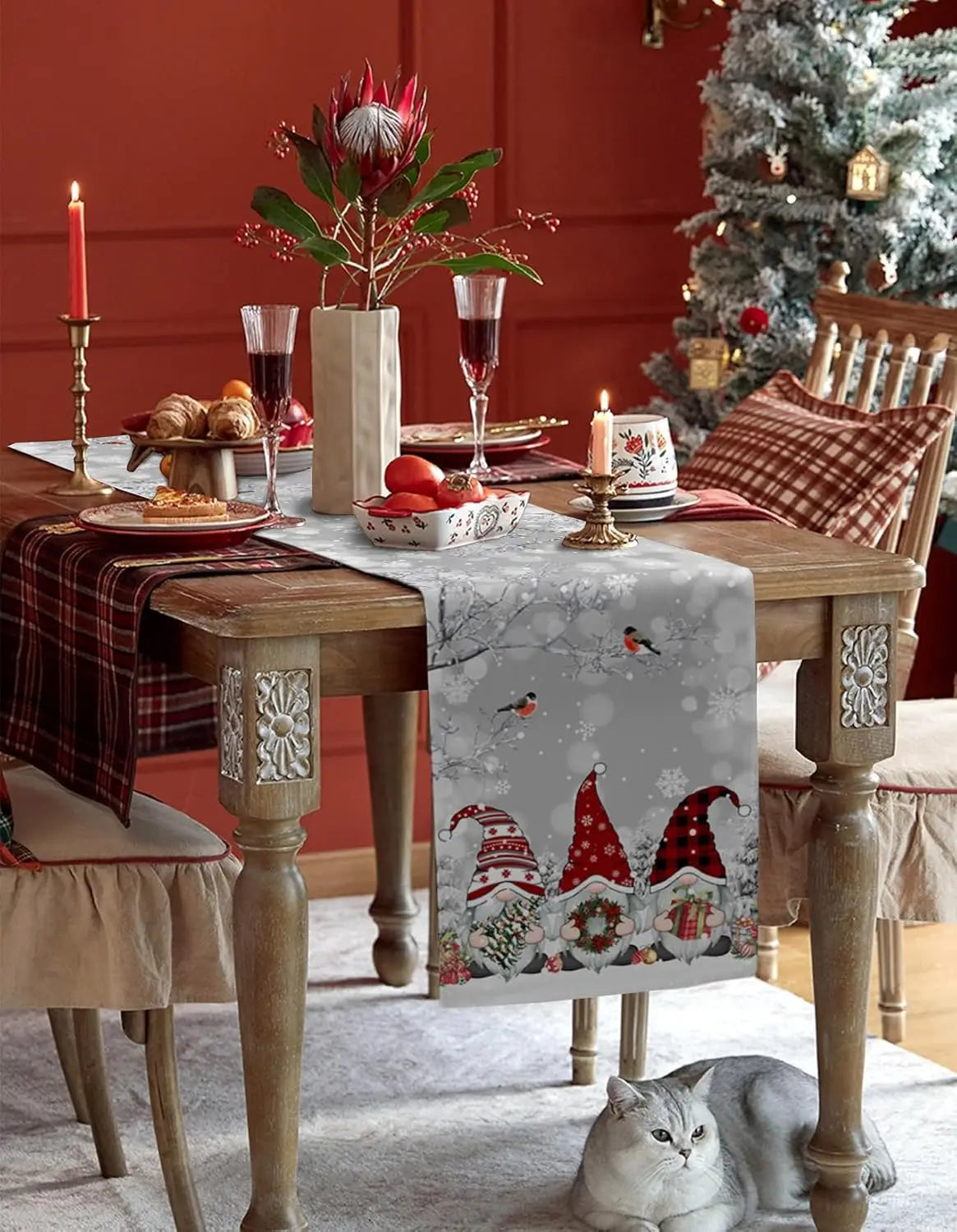 Une table de Noël festive avec de beaux éléments décoratifs, une chaise en bois et un chat gris assis sous la table.
