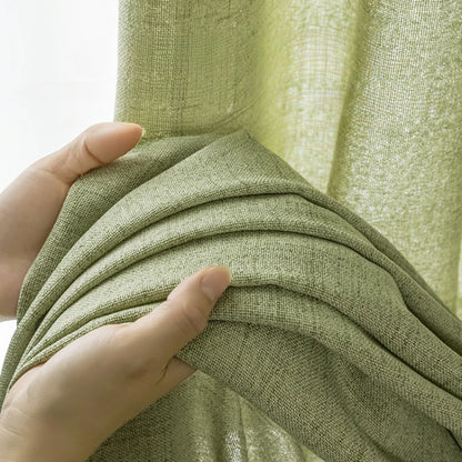 Zoom sur la texture épaisse et naturelle du rideau vert amande tenu dans une main.