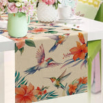 Nappe de table avec motif de colibris et fleurs tropicales colorées dans des teintes chaudes, créant une ambiance estivale et raffinée.
