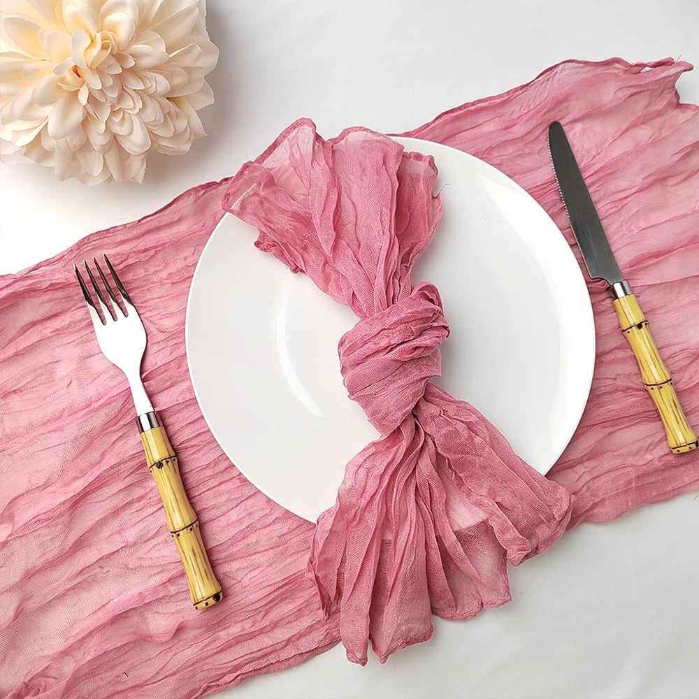 Une table élégante avec des couverts dorés, une serviette en tissu rose et une belle fleur blanche, créant une ambiance chaleureuse et raffinée.