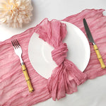 Une table élégante avec des couverts dorés, une serviette en tissu rose et une belle fleur blanche, créant une ambiance chaleureuse et raffinée.