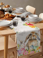 Un élégant service de table en porcelaine blanche accompagné de pains dorés et de divers accessoires de cuisine sur un joli chemin de table fleuri.