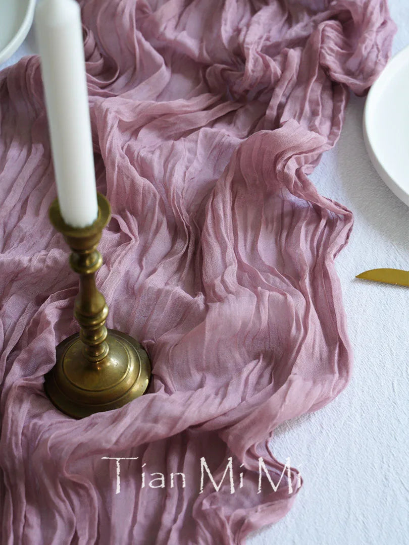 Composition de Tissu froissé rose et bougie dorée sur fond blanc, créant une ambiance élégante et raffinée.