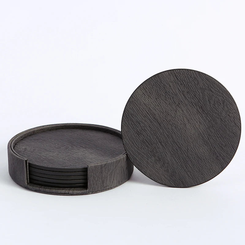 Un ensemble de dessous de verre noirs en bois texturés, empilés les uns sur les autres.