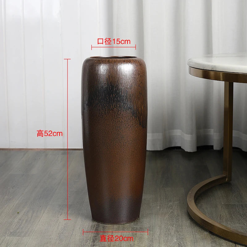 Un grand vase en céramique brun foncé décoratif posé sur le sol, mesurant 52 cm de hauteur et 15 cm de diamètre.