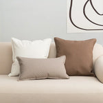 Des coussins décoratifs en différentes tailles et textures sur un canapé blanc, créant une ambiance chaleureuse et confortable dans l'espace.
