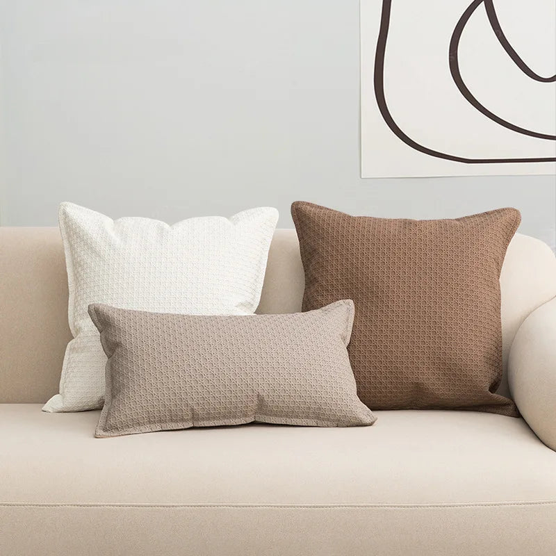 Des coussins décoratifs en différentes tailles et textures sur un canapé blanc, créant une ambiance chaleureuse et confortable dans l'espace.