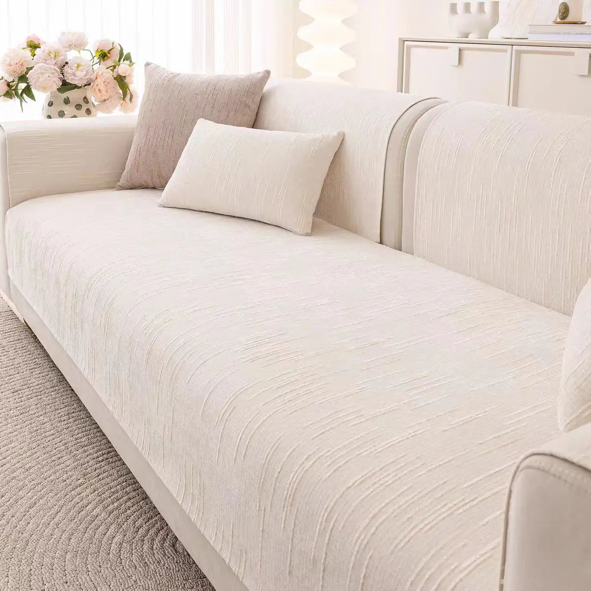 Un canapé moelleux et confortable, avec des coussins texturés et une composition florale élégante, dans un décor lumineux et épuré.