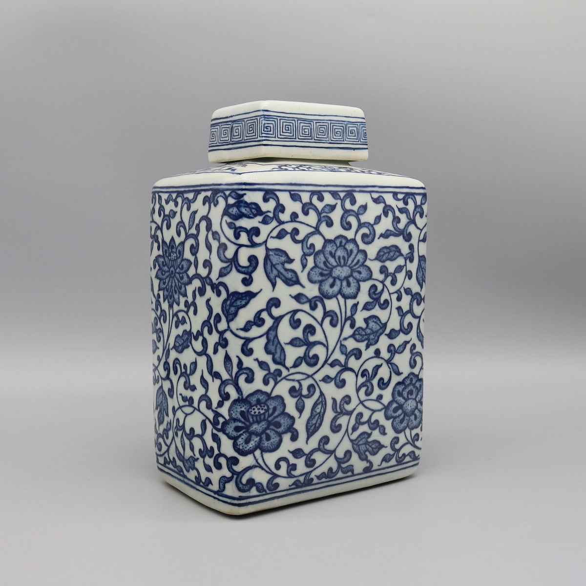 Jarre décorative en céramique blanche et bleue ornée de motifs floraux élégants.