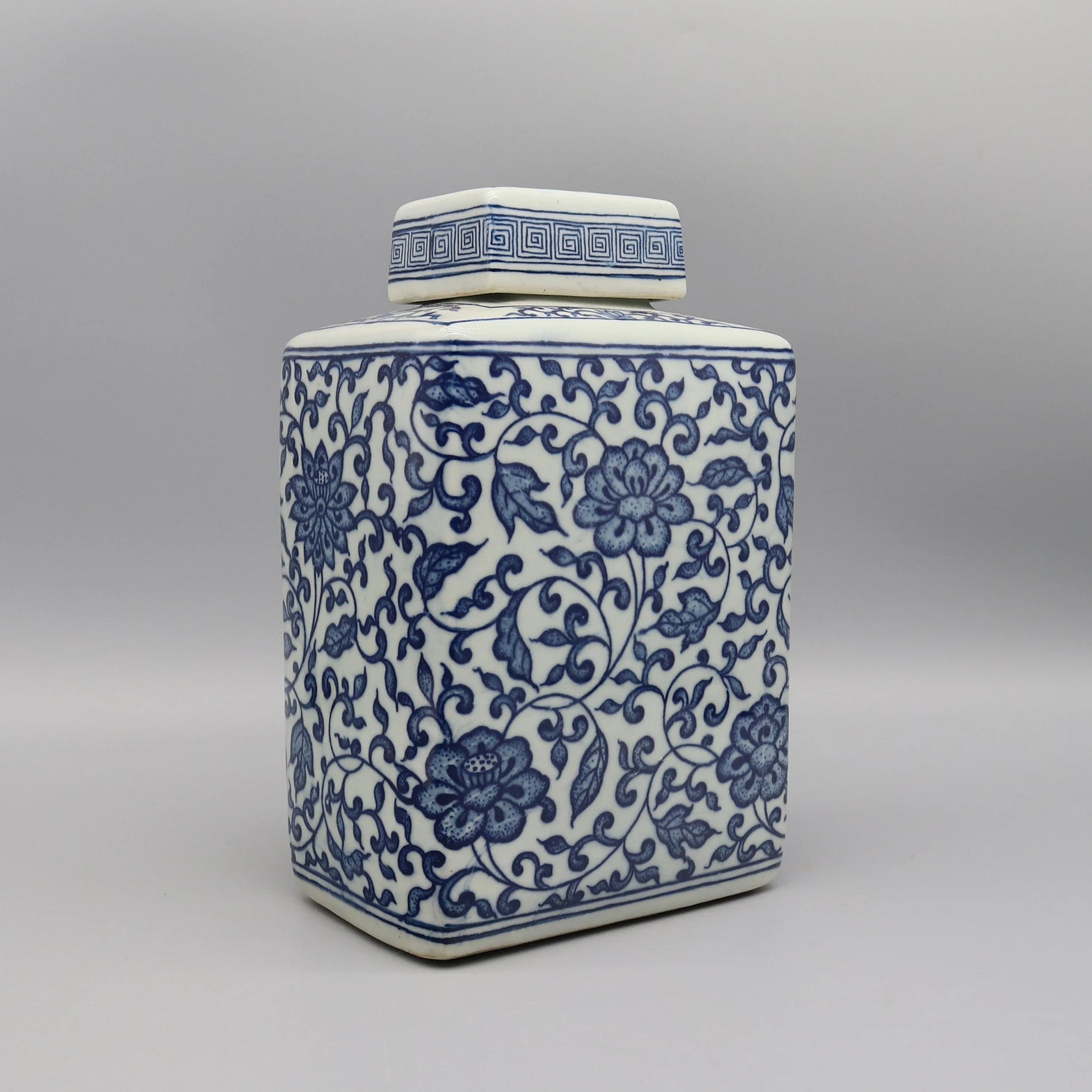 Jarre décorative en céramique blanche et bleue ornée de motifs floraux élégants.