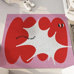 Tapis décoratif rose et rouge avec motif de personnages aux formes organiques et le texte "Have a good day!!" en son centre.