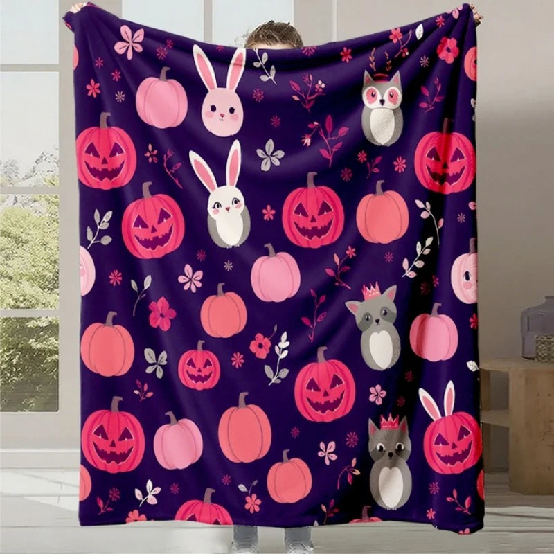 Cette image montre une couverture ou un plaid de type Halloween avec des motifs de citrouilles, lapins et autres animaux sur un fond violet foncé.