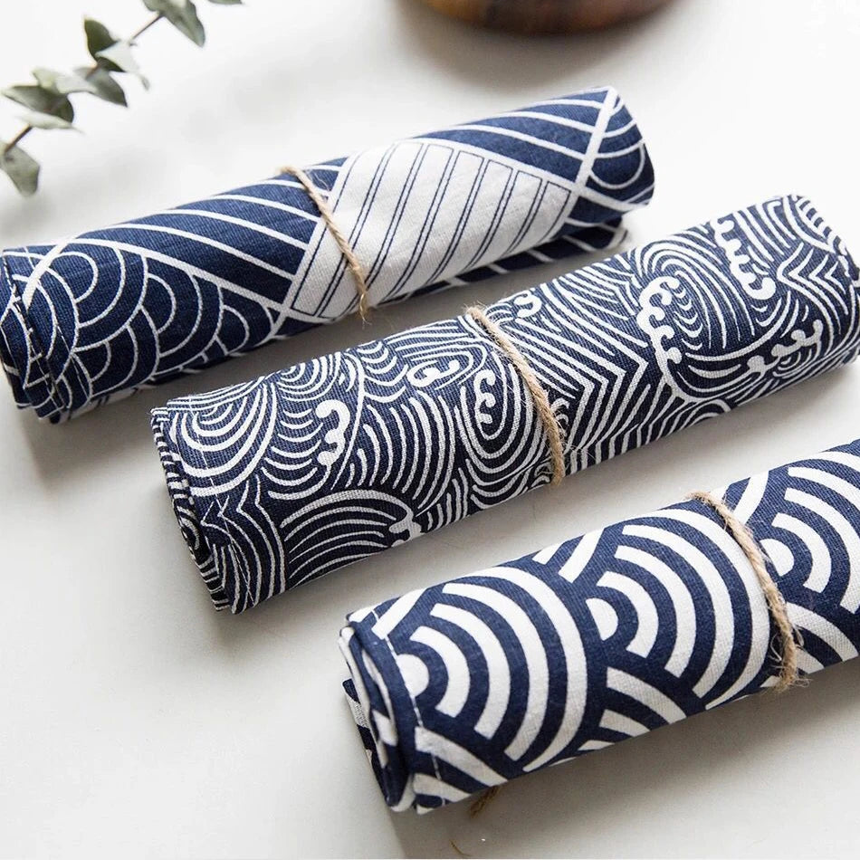 Des rouleaux de tissu avec des motifs géométriques bleus et blancs, enroulés et attachés avec de la ficelle.