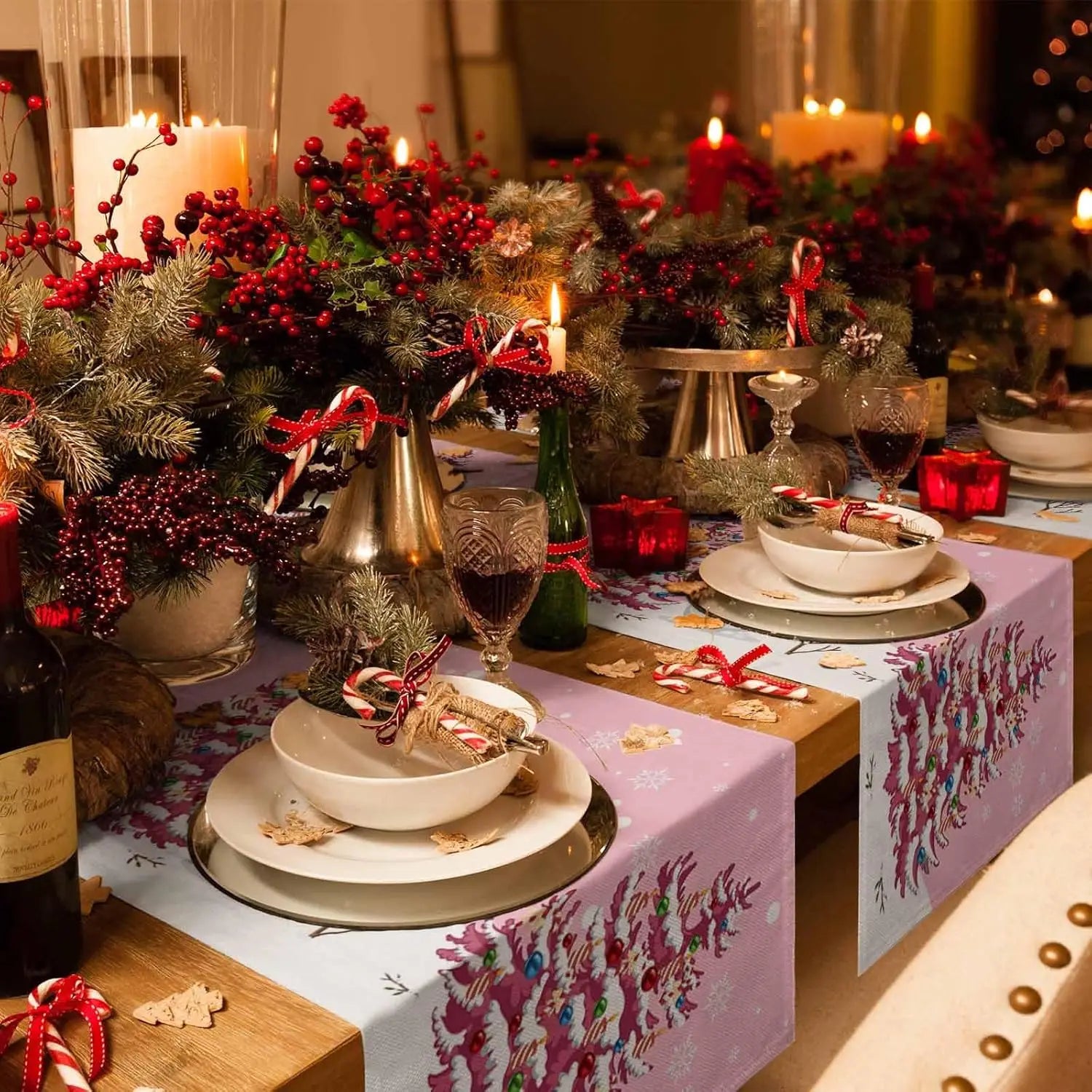 Une table élégamment décorée pour les fêtes avec des bougies, des branches de sapin, des baies rouges et des décorations dorées créant une ambiance chaleureuse et festive.