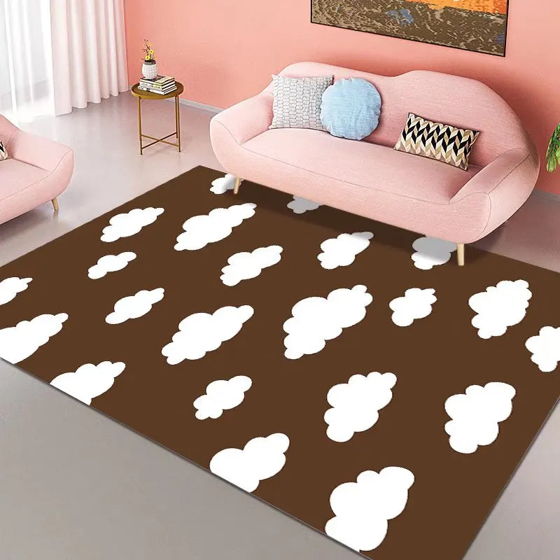 Le salon aux murs roses comprend un canapé rose ainsi que de nombreux coussins colorés posés sur un tapis marron décoré de nuages blancs.