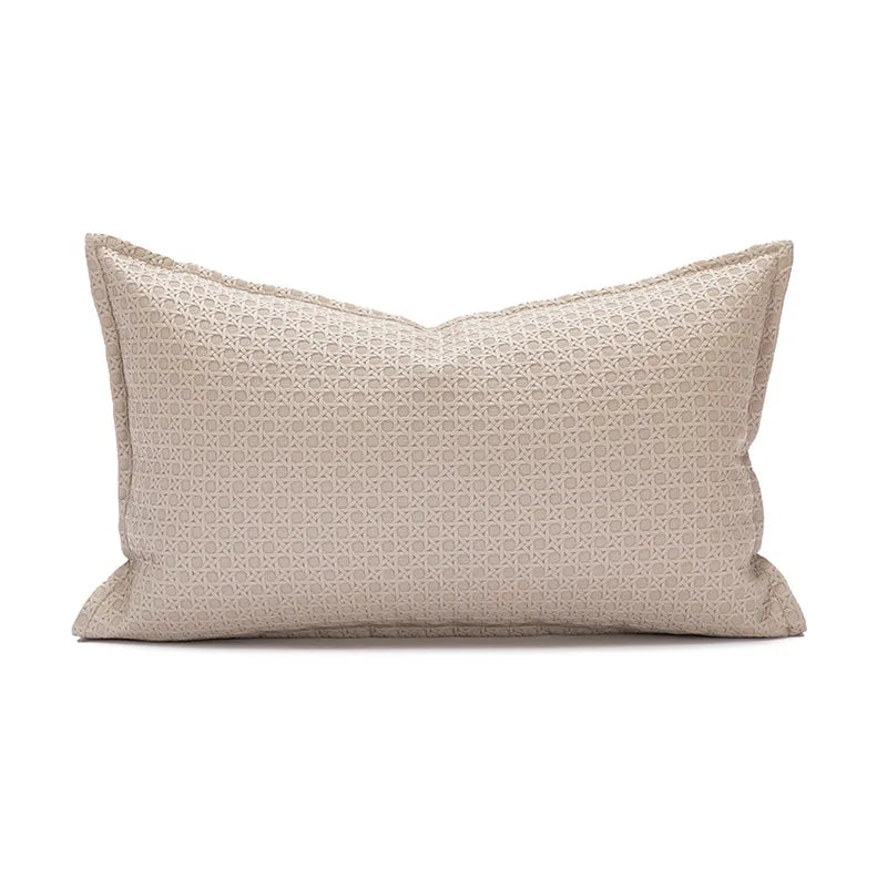 Coussin décoratif beige avec un motif géométrique discret.