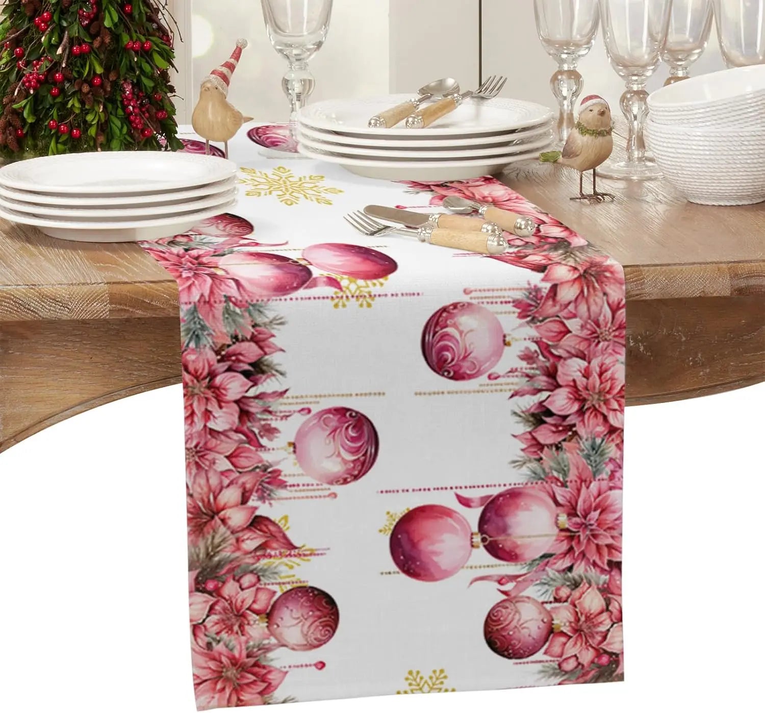 Des décorations de Noël élégantes avec des ornements et des fleurs roses sur une table dressée.