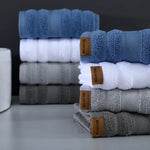 Piles de serviettes de bain bleues, blanches et grises emballées avec des étiquettes marron.