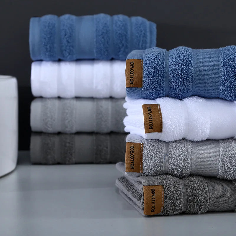 Piles de serviettes de bain bleues, blanches et grises emballées avec des étiquettes marron.