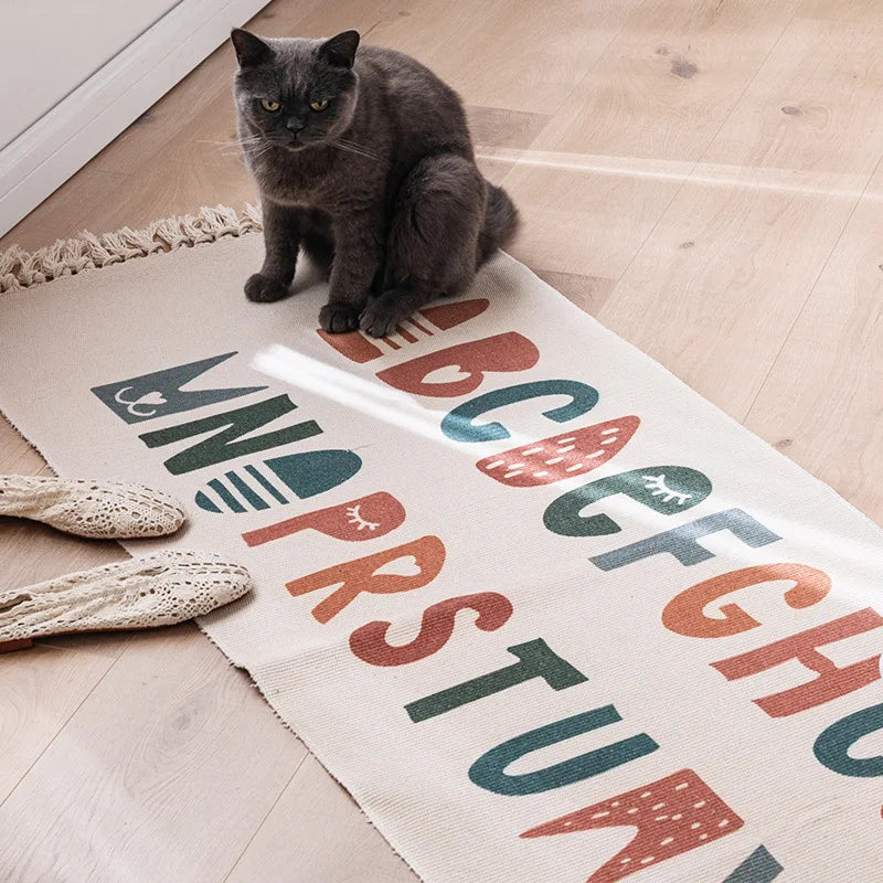 Un chat gris assis sur un tapis avec des motifs colorés.