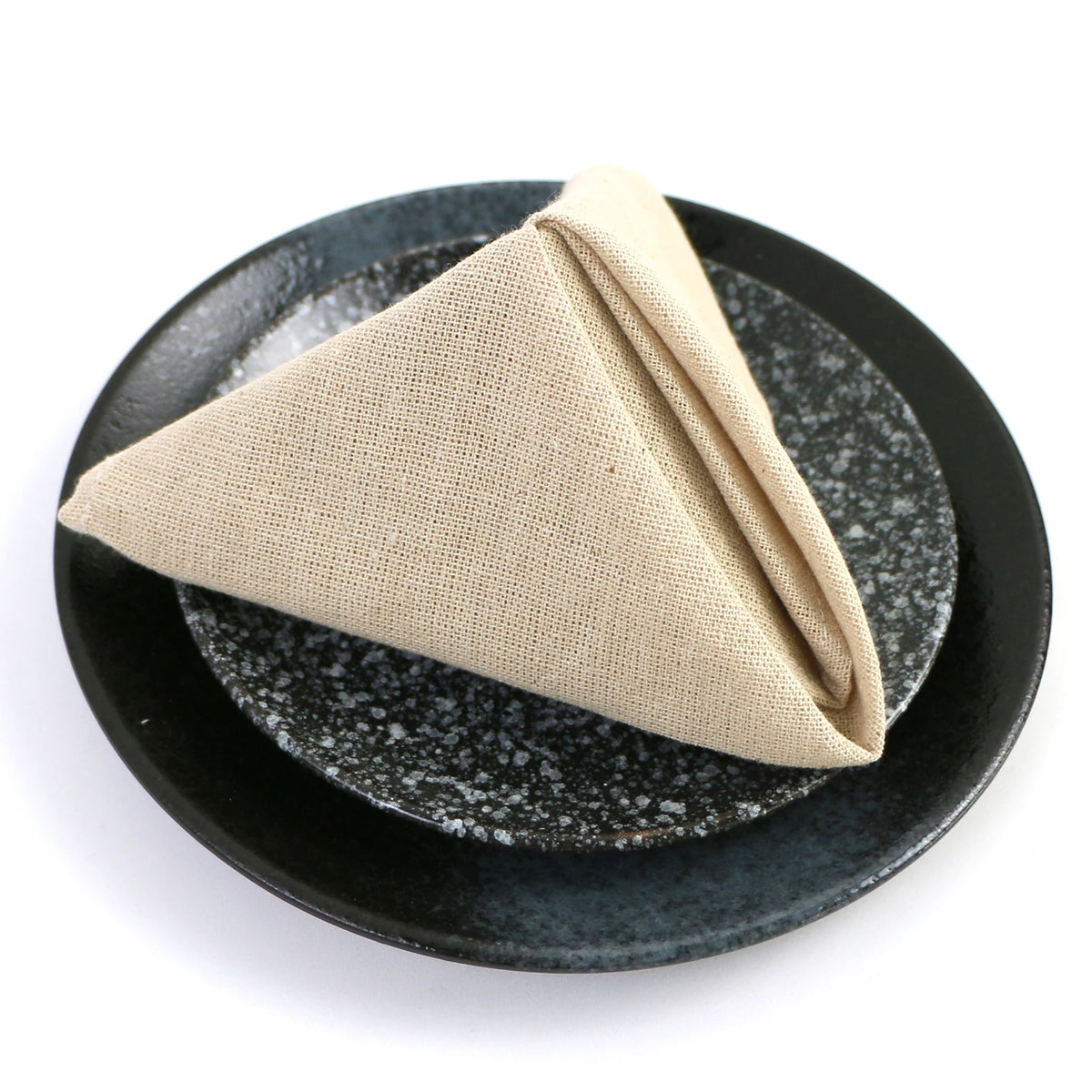 Serviette beige pliée sur un plat en céramique noir avec un motif texturé.