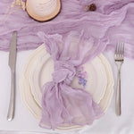 Une magnifique table de banquet décorée avec élégance, mettant en valeur des assiettes blanches, des couverts argentés et une belle nappe violette ornée de délicates fleurs.