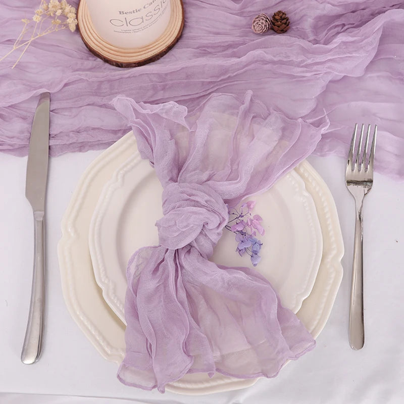 Une magnifique table de banquet décorée avec élégance, mettant en valeur des assiettes blanches, des couverts argentés et une belle nappe violette ornée de délicates fleurs.