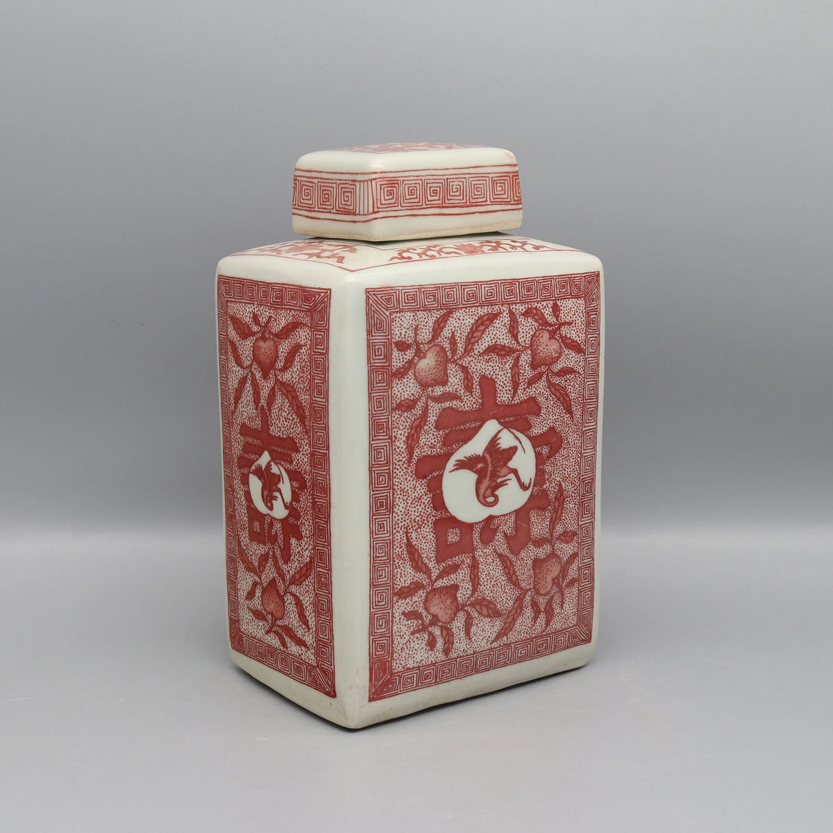 Pot décoratif en céramique blanche avec motifs floraux rouges et géométriques.