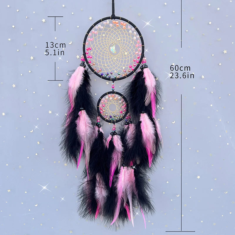 Le rêve attrapeur en forme de cercle, avec des plumes roses et noires, décoré d'éléments brillants et suspendu sur un fond étoilé.