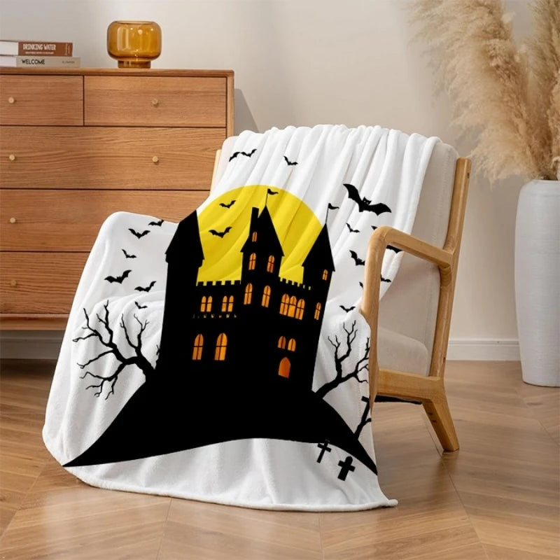 Une couverture blanche ornée d'un château hanté en noir et jaune avec des chauves-souris volant au-dessus, évoquant l'ambiance d'Halloween.