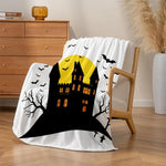 Une couverture blanche ornée d'un château hanté en noir et jaune avec des chauves-souris volant au-dessus, évoquant l'ambiance d'Halloween.