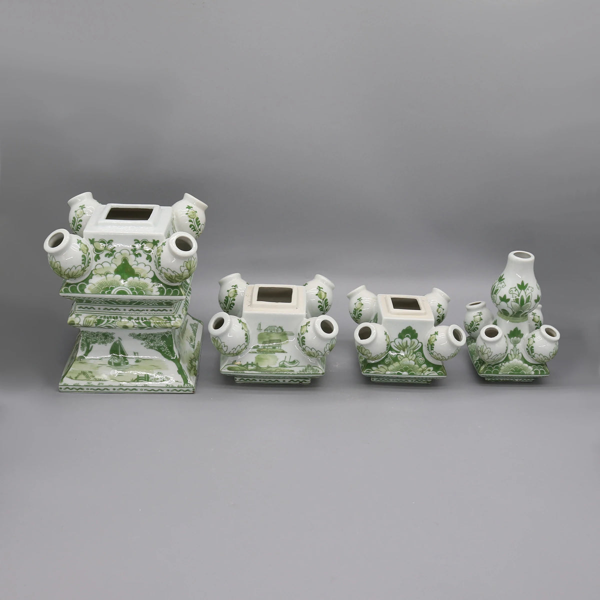 Ensemble décoratif de porcelaine blanche et verte orné de motifs floraux, composé de plusieurs vases et pots aux formes élégantes.