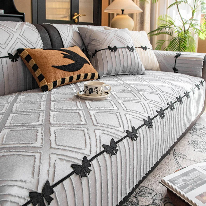 Le canapé gris est décoré de motifs géométriques blancs et noirs ainsi que de coussins ornés de papillons noirs, créant une atmosphère sophistiquée et harmonieuse dans ce salon confortable.