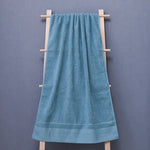 Une serviette de bain bleue pâle suspendue sur un porte-serviette en bois, offrant un look élégant et relaxant dans une salle de bain.
