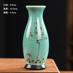 Un vase en porcelaine turquoise orné d'une délicate fleur de lotus peinte en brun.