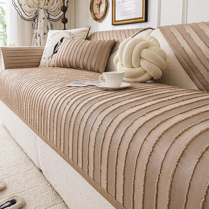 Cette image montre un canapé beige avec des motifs rayés et des coussins décoratifs, donnant un aspect confortable et élégant à l'espace.