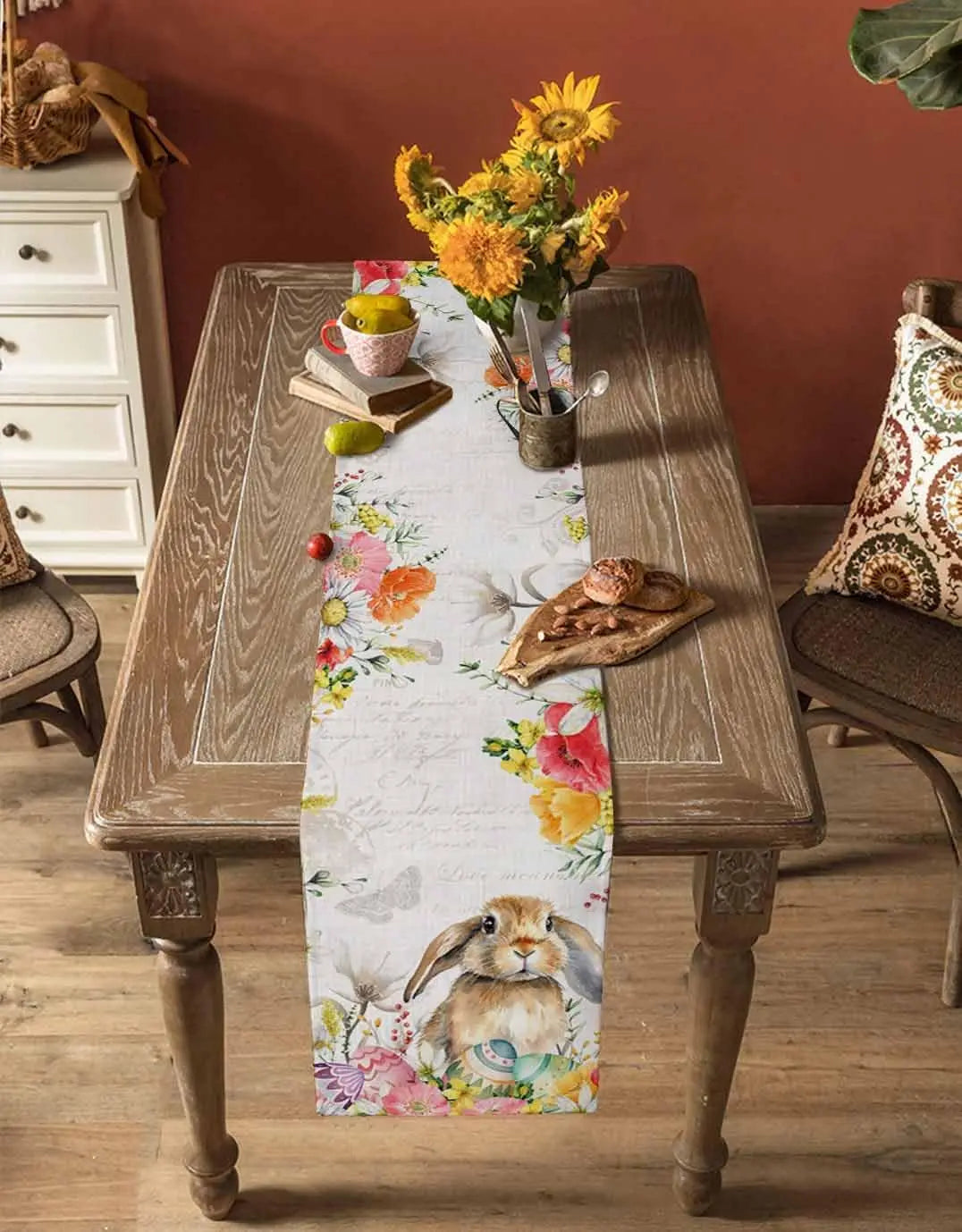 Une belle table de salle à manger rustique avec un bouquet de fleurs colorées, des fruits et un motif de lapin printanier sur un chemin de table fleuri.
