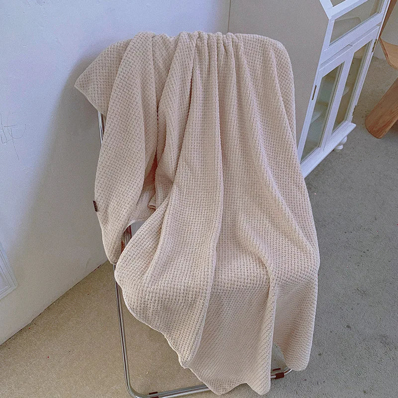 Une couverture de tricot douce et confortable dans des tons neutres, posée sur un meuble, créant une ambiance chaleureuse et accueillante.