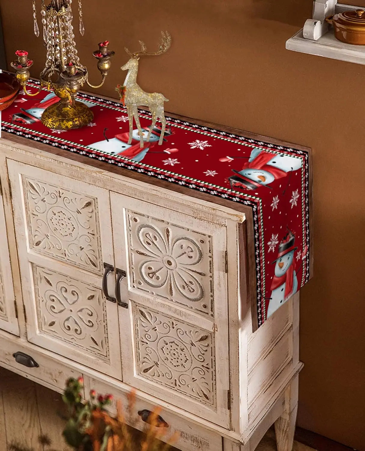 Commode en bois décorative avec motifs sculptés et accessoires de Noël posés sur le dessus, créant une ambiance chaleureuse et festive.