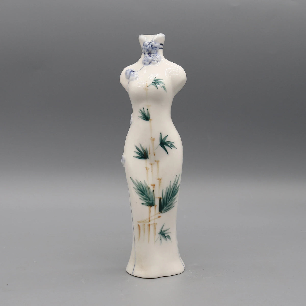 Vase en porcelaine délicat avec motifs floraux bleu et vert sur un fond blanc crème.
