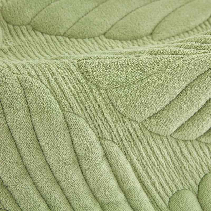Texture en relief de fibres vertes douces et moelleuses, formant un motif de vagues et de lignes courbes, créant un effet visuel apaisant et naturel.