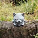 ornement zen statue chat gris allongé texture pierreuse jardin fleurs plantes