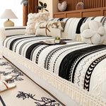 Lit couvre-lit décoré de motifs géométriques noirs et blancs avec des franges, entouré d'accessoires d'intérieur dans un style cosy et confortable.