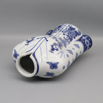 Vase décoratif blanc et bleu avec des motifs floraux et des papillons.