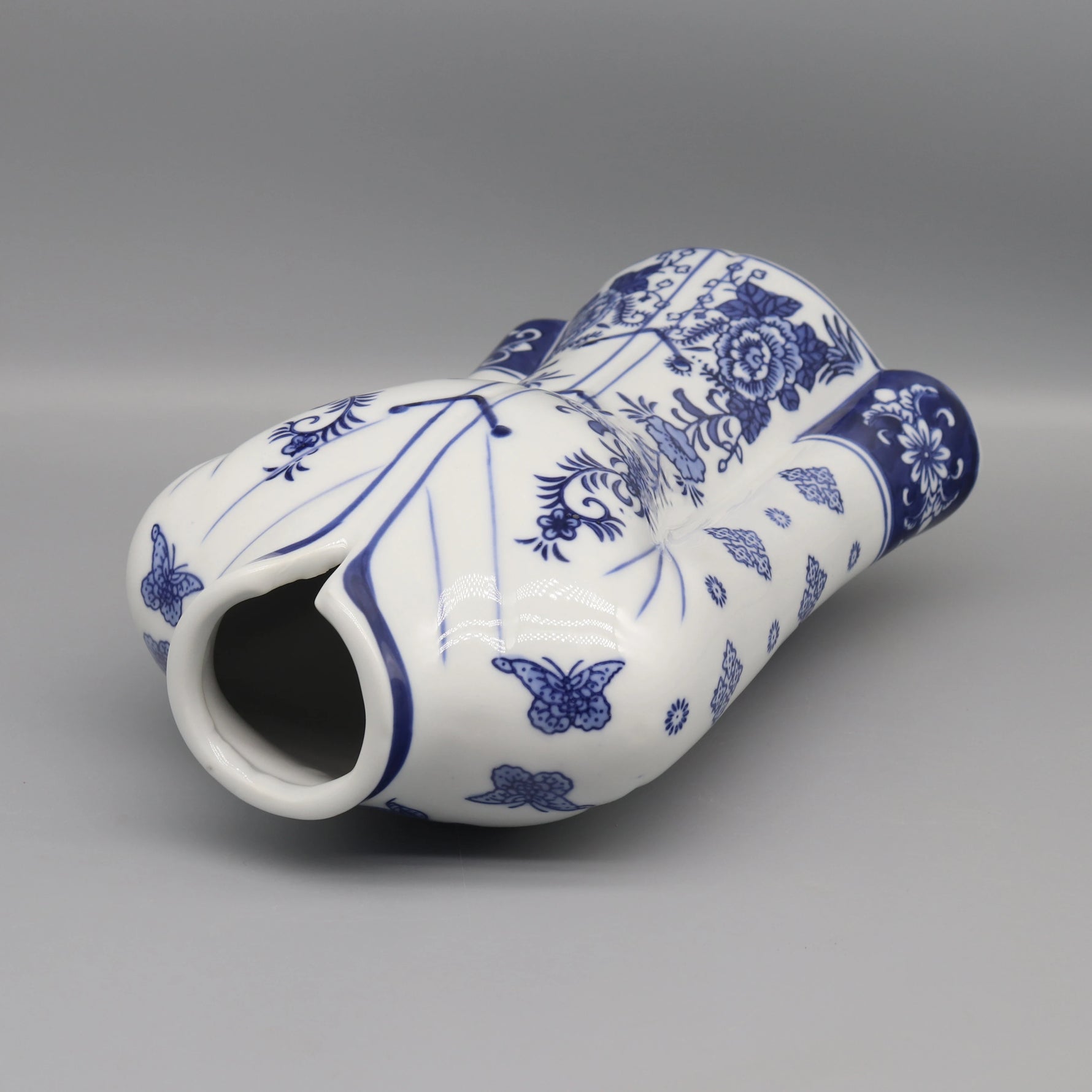 Vase décoratif blanc et bleu avec des motifs floraux et des papillons.