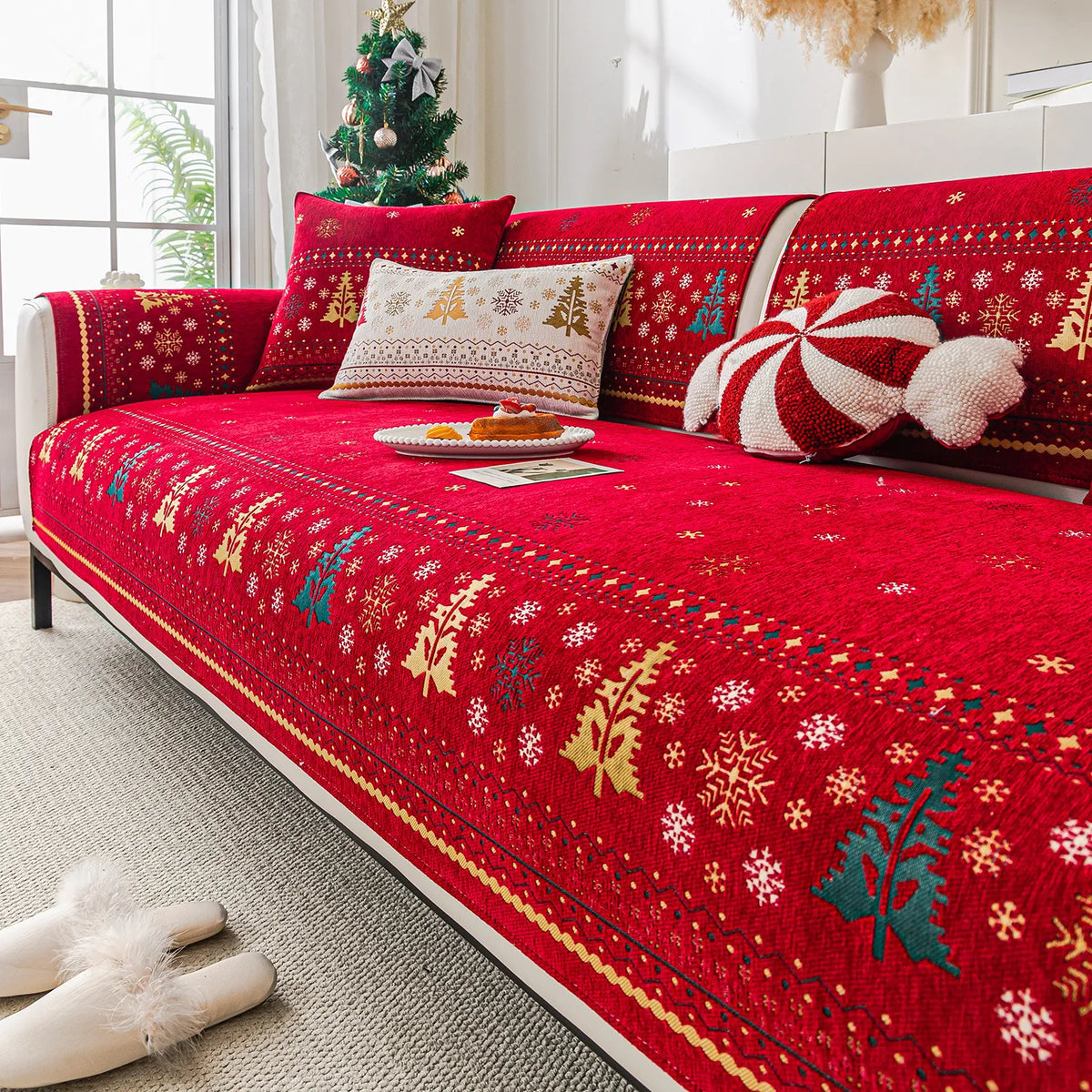 Un canapé rouge avec des motifs hivernaux et des décorations de Noël, créant une atmosphère chaleureuse et festive.